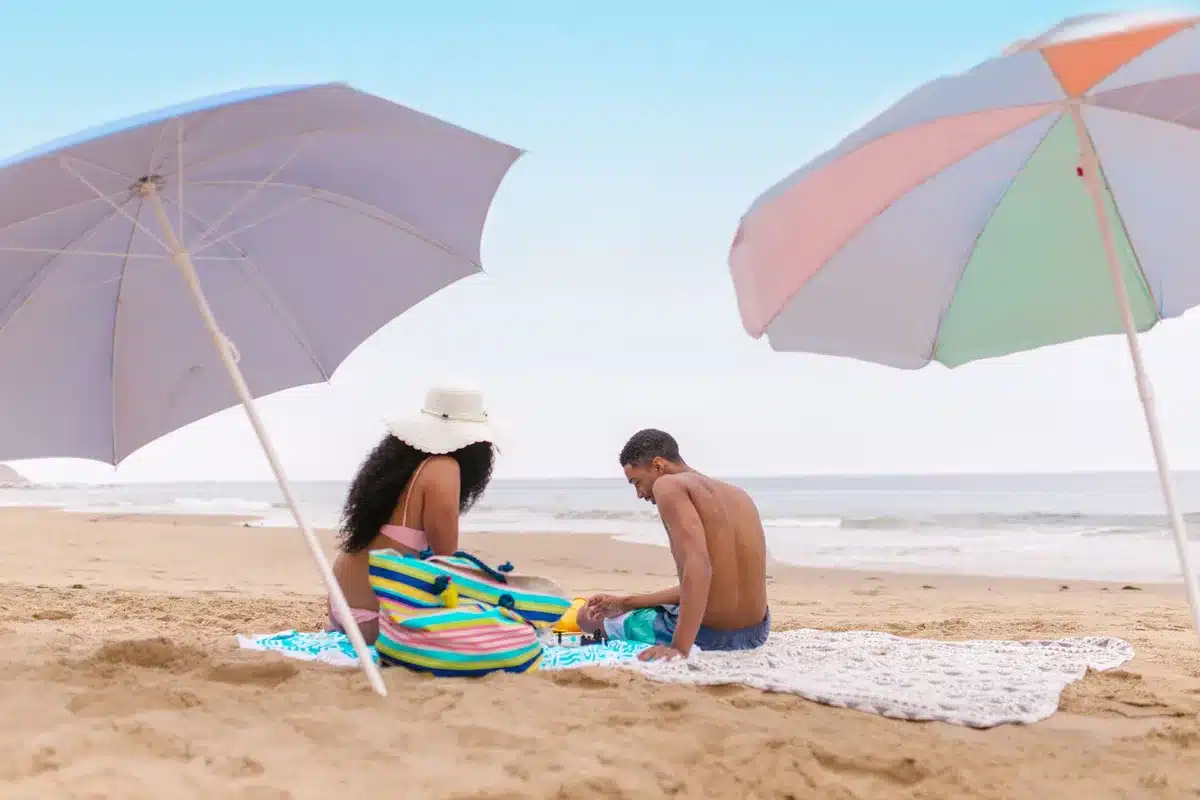 Spiaggia con ombrelloni colorati, asciugamani e bagnanti che si godono il mare