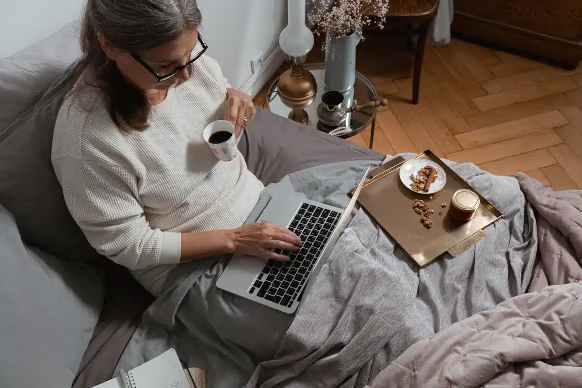 Donna anziana che fa colazione con caffellatte e biscotti al mattino