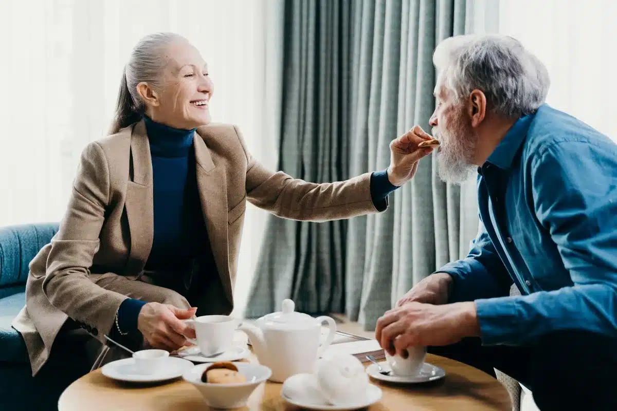 Una donna anziana con una tazza di caffè caldo e biscotti al cioccolato a colazione, luce mattutina