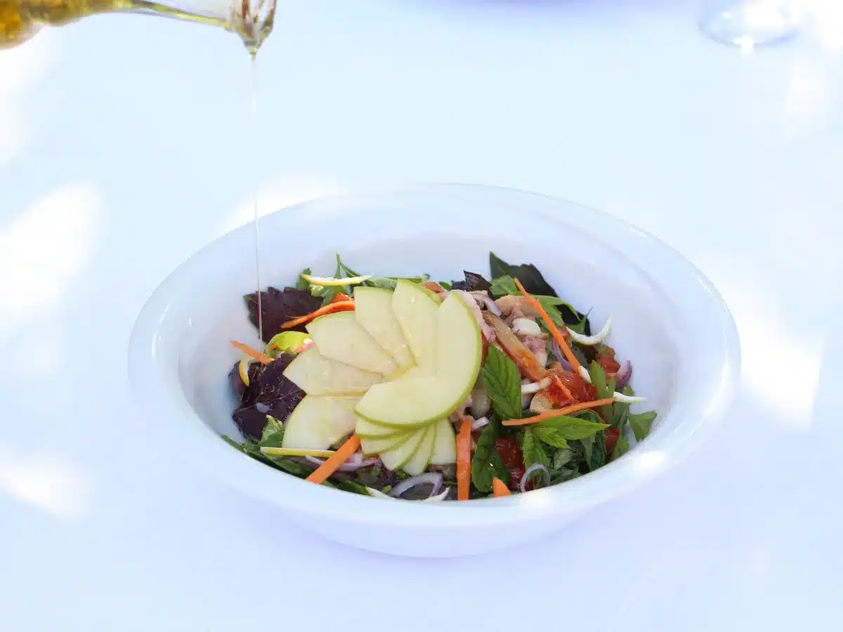 Olio d'oliva versato su un'insalata fresca con verdure varie