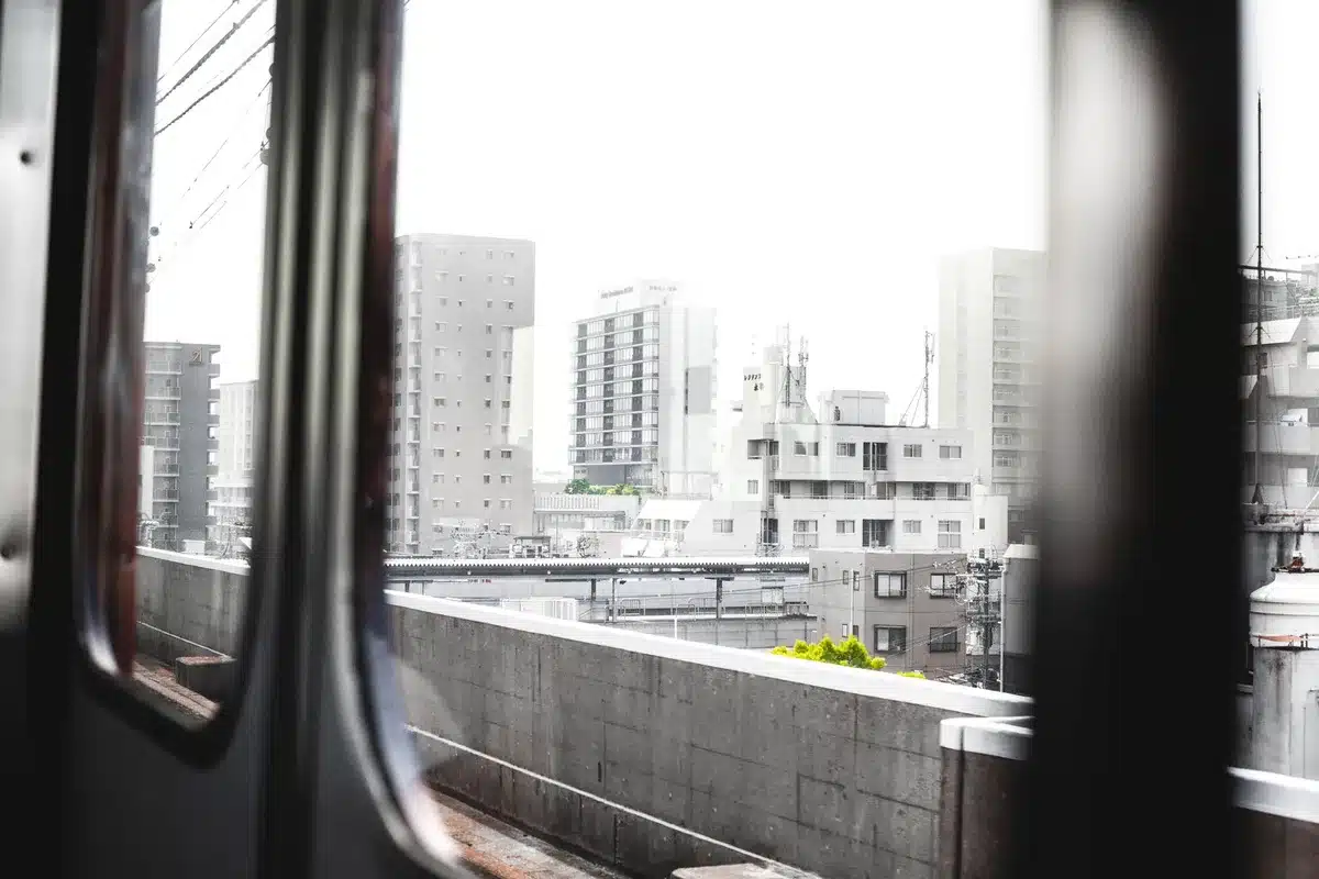Vista dalla finestra di un treno giapponese con montagne e paesaggi urbani sfocati