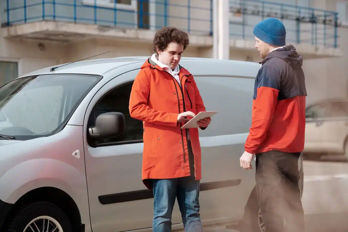 Two people exchanging a package through a car window during a crowdshipping delivery